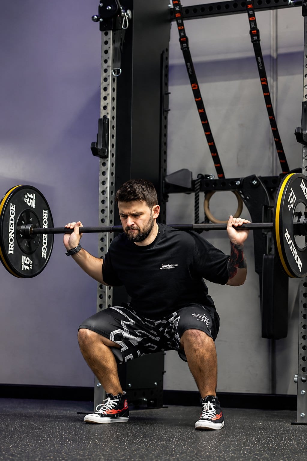 Dan performing a barbell back squat in an Injury Active shirt