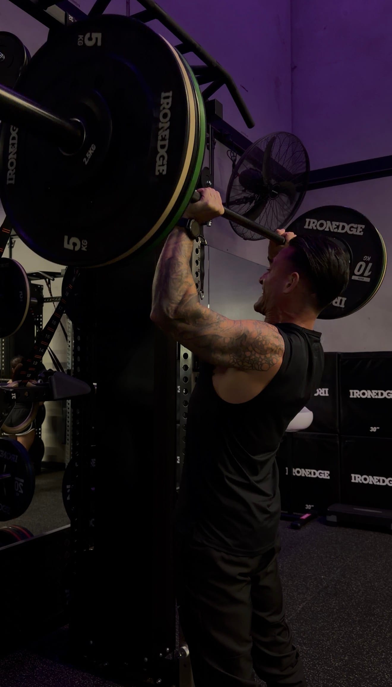 Craig performing a strict overhead press in the gym